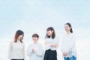 4 donne giapponesi che indossano top bianchi e parlano con un sorriso