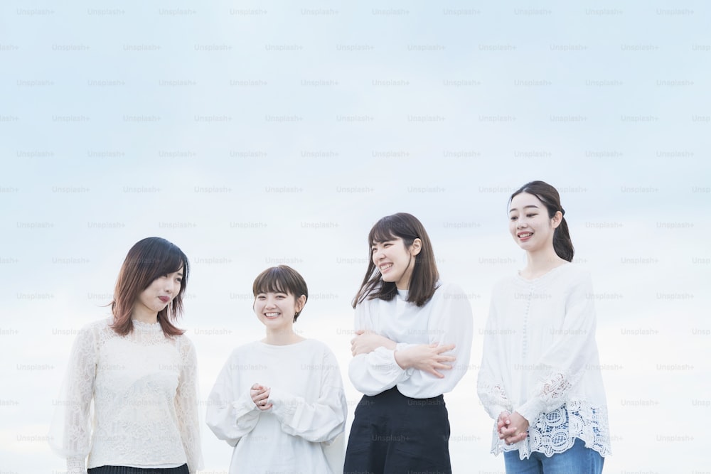 4 Japanese women wearing white tops and talking with a smile