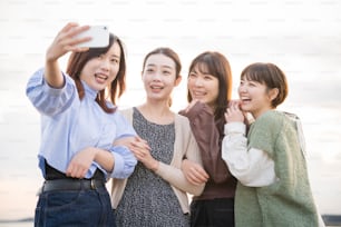 4 mujeres jóvenes tomando una foto conmemorativa con un teléfono inteligente