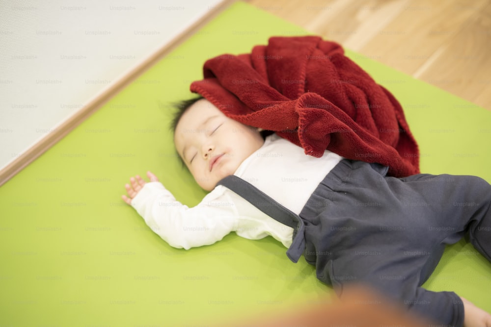 Asian male baby sleeping comfortably on a mat indoors