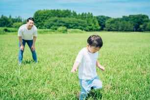 A boy running in the meadow and a father watching over on fine day
