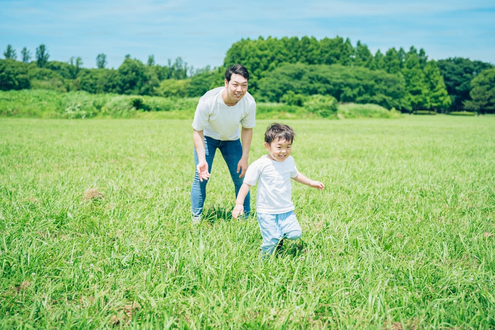 Un niño corriendo por el prado y un padre vigilando en buen día