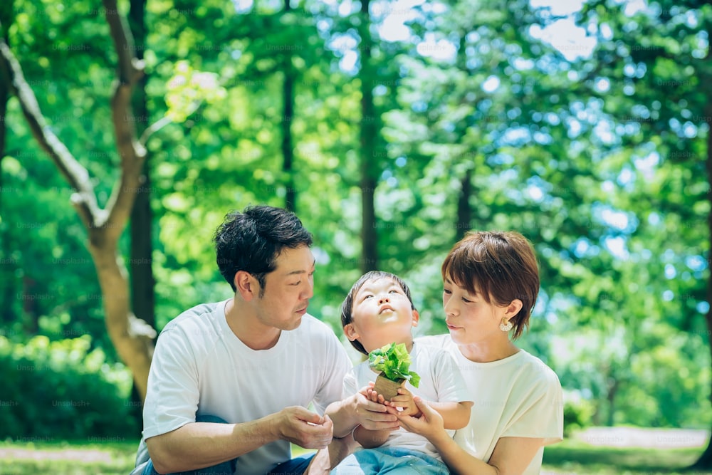 A family with a small potted plant in the woods on fine day