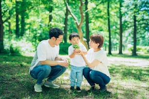 晴れた日に森の中に小さな鉢植えの植物を持つ家族