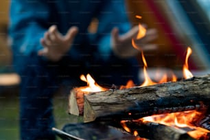 A man enjoying a bonfire in front of tent