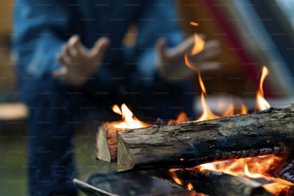 A man enjoying a bonfire in front of tent