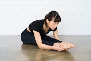 A woman doing a forward bending exercise indoors
