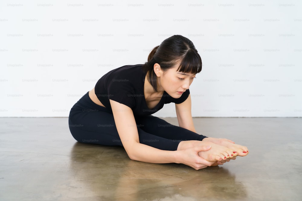 Una mujer haciendo un ejercicio de flexión hacia adelante en interiores