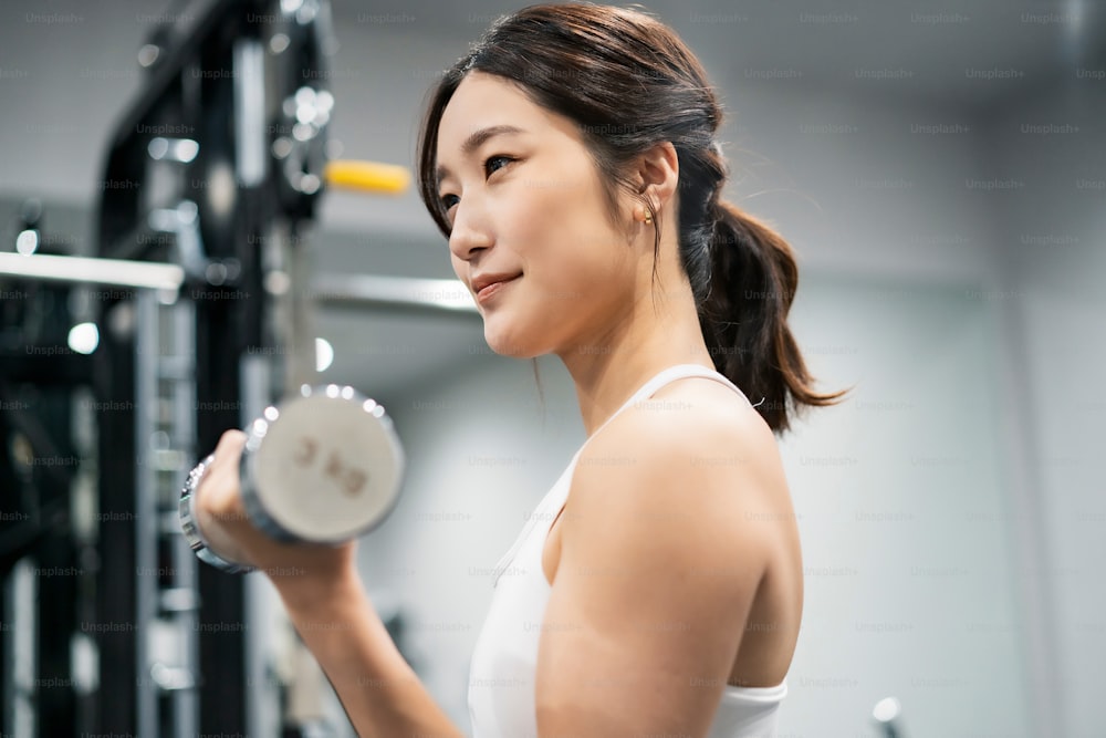 Asiatische junge Frau macht Muskeltraining mit Hanteln