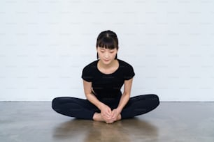 Eine Frau, die Yoga in einer Sohlenpose in Innenräumen macht