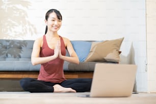 Uma mulher que faz yoga enquanto olha para a tela do computador na sala