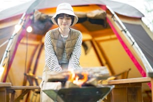 Una donna che si gode un falò davanti alla tenda
