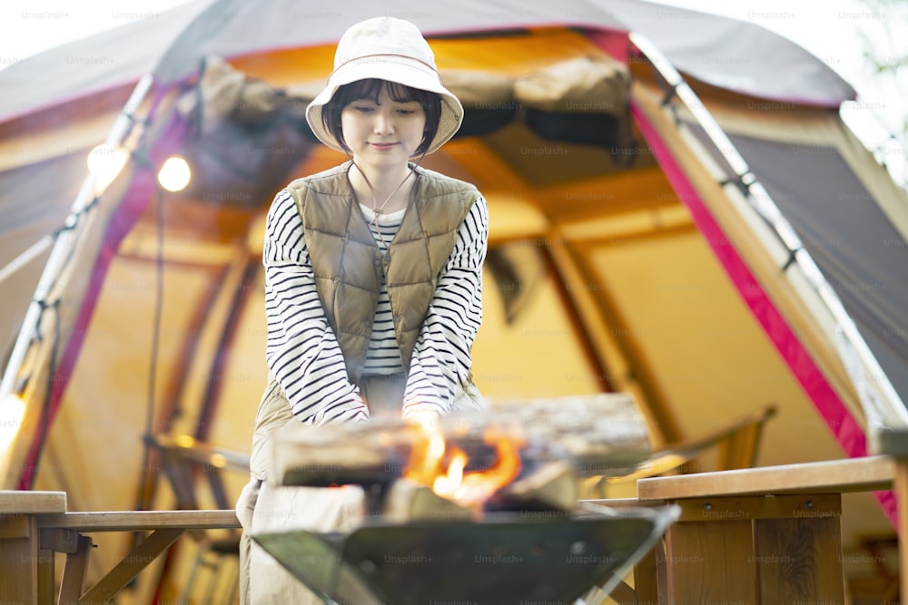 A woman enjoying a bonfire in front of tent