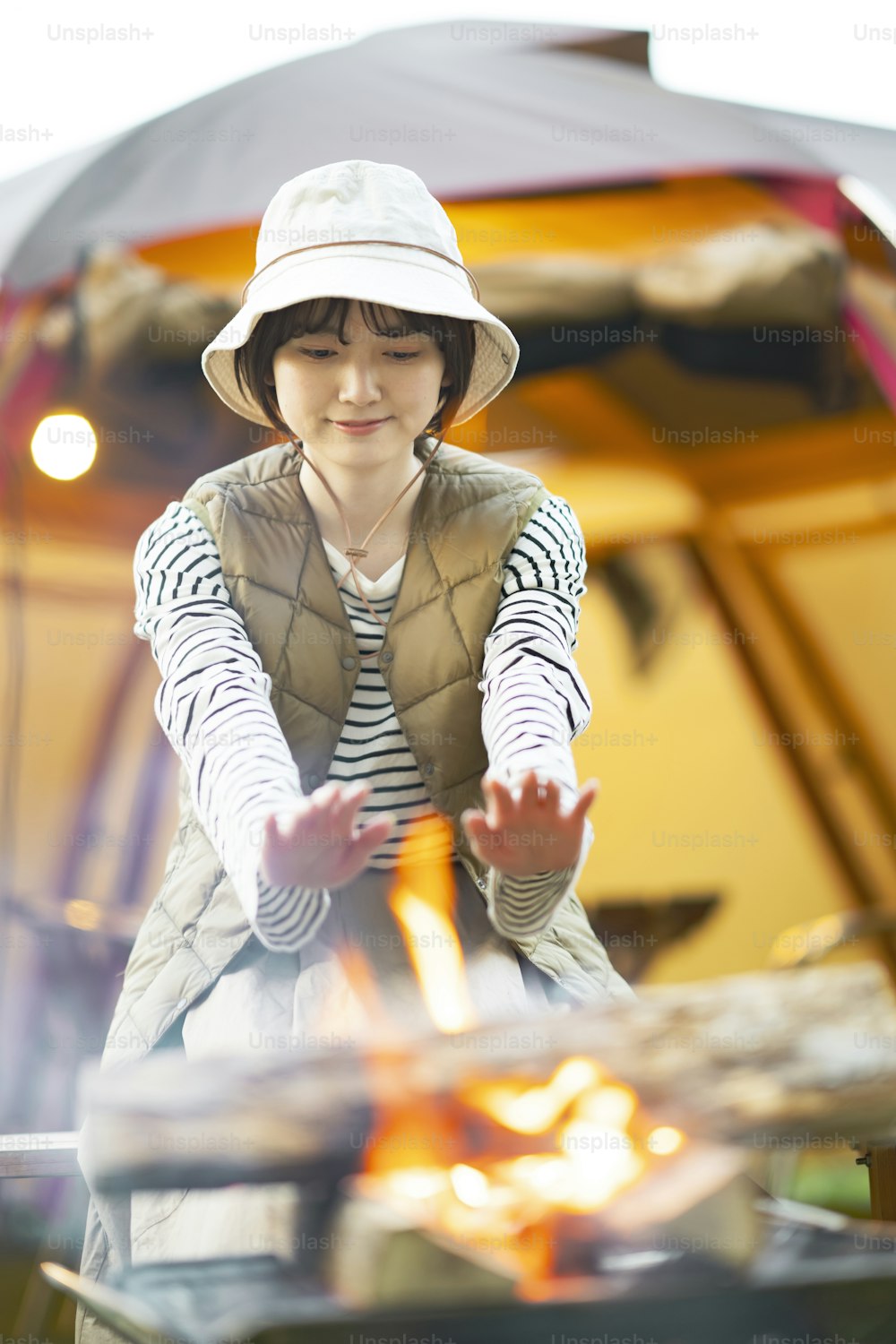 A woman enjoying a bonfire in front of tent