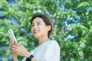 Junge Frau hält ein Smartphone im Freien