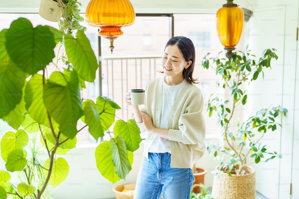 Femme asiatique se relaxant entourée de plantes à feuillage