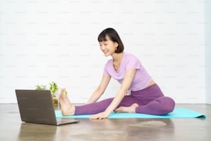 A woman taking an online yoga lesson using a laptop