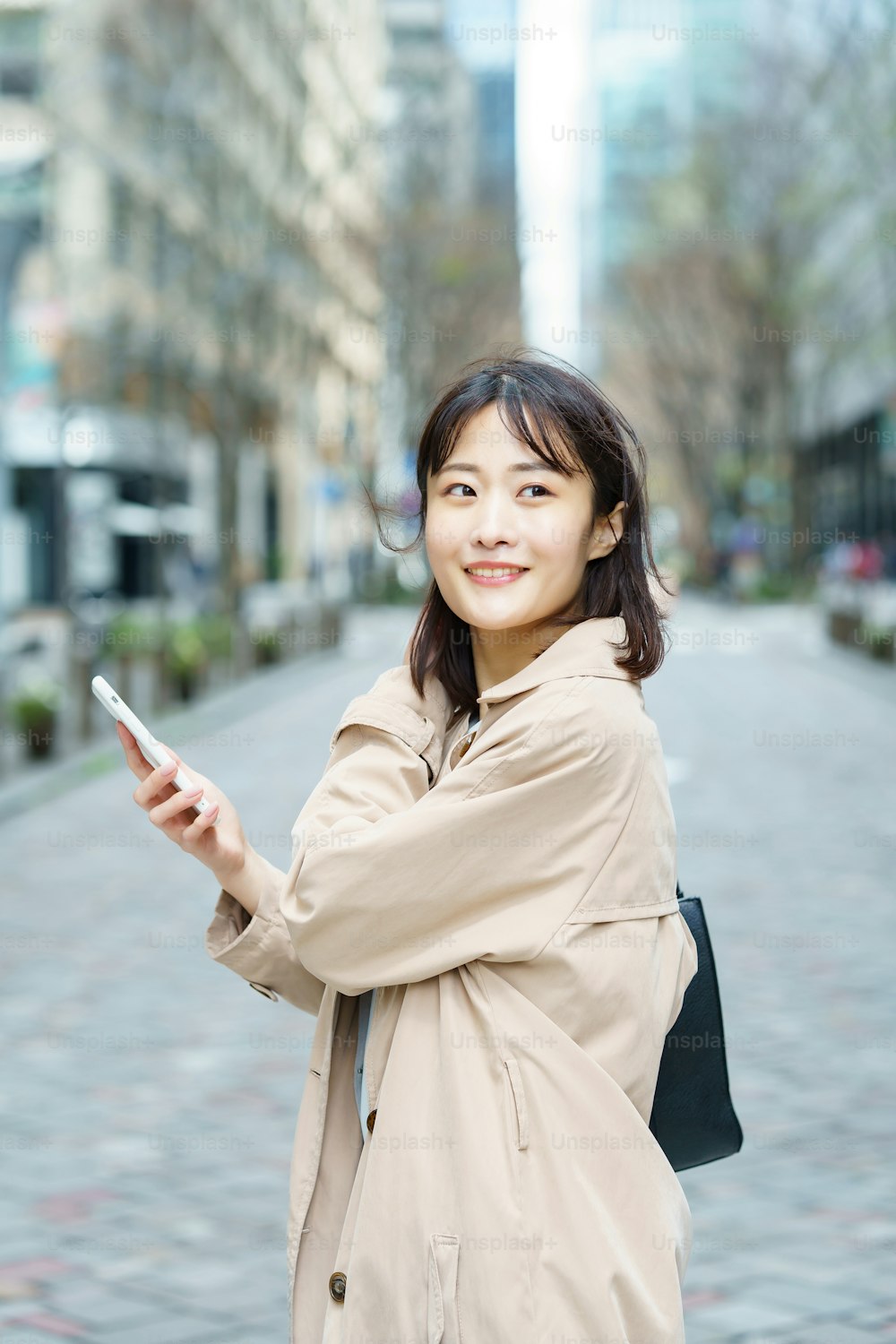 Eine Frau, die mit einem Smartphone in der Hand in einem Geschäftsviertel spazieren geht