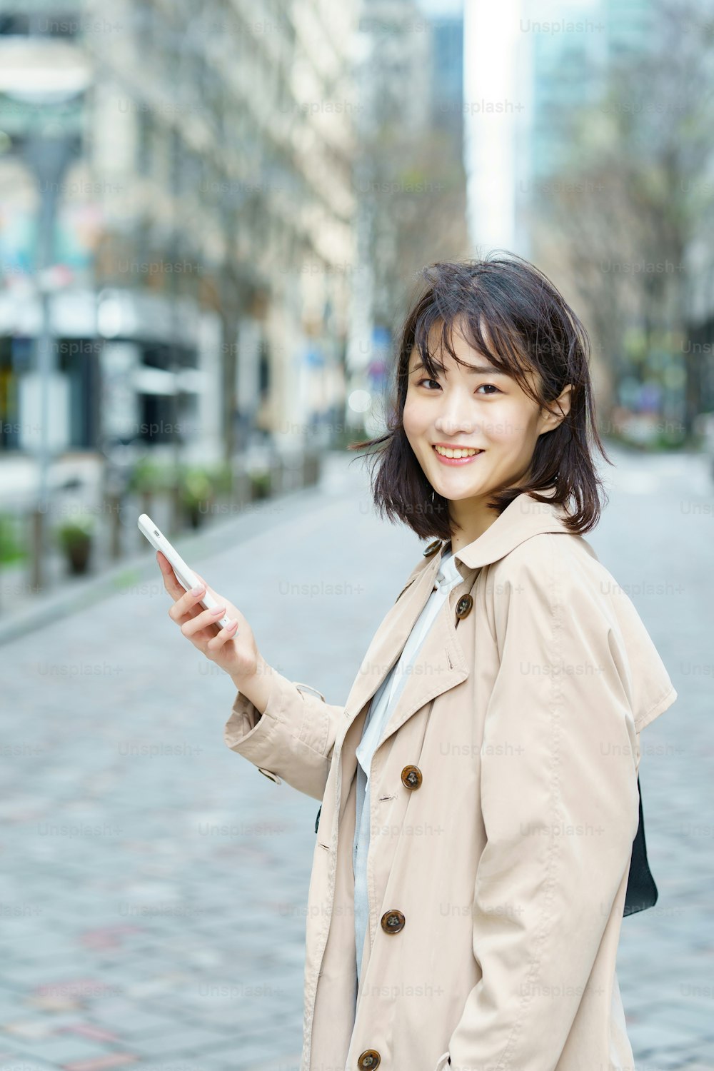 Una donna che cammina in un quartiere degli affari con uno smartphone in mano