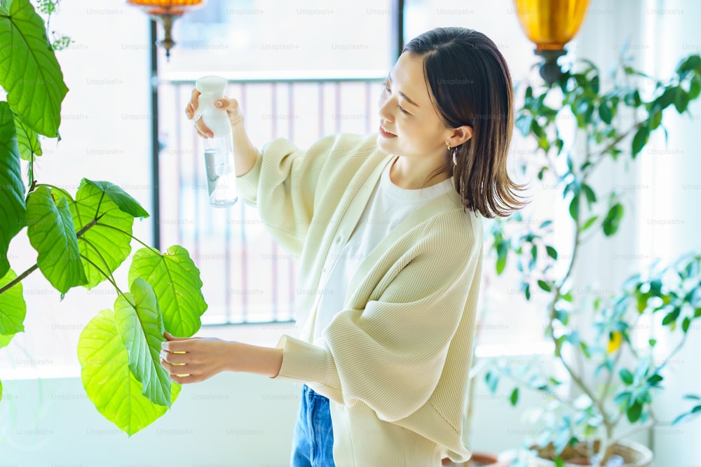 A woman watering a houseplant in a room