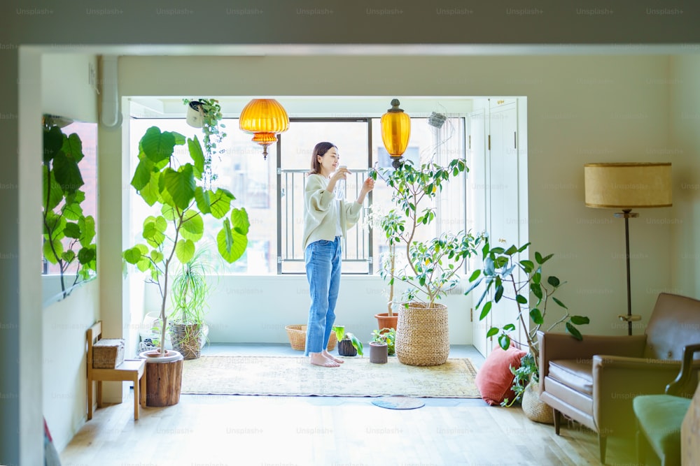 A woman watering a houseplant in a room