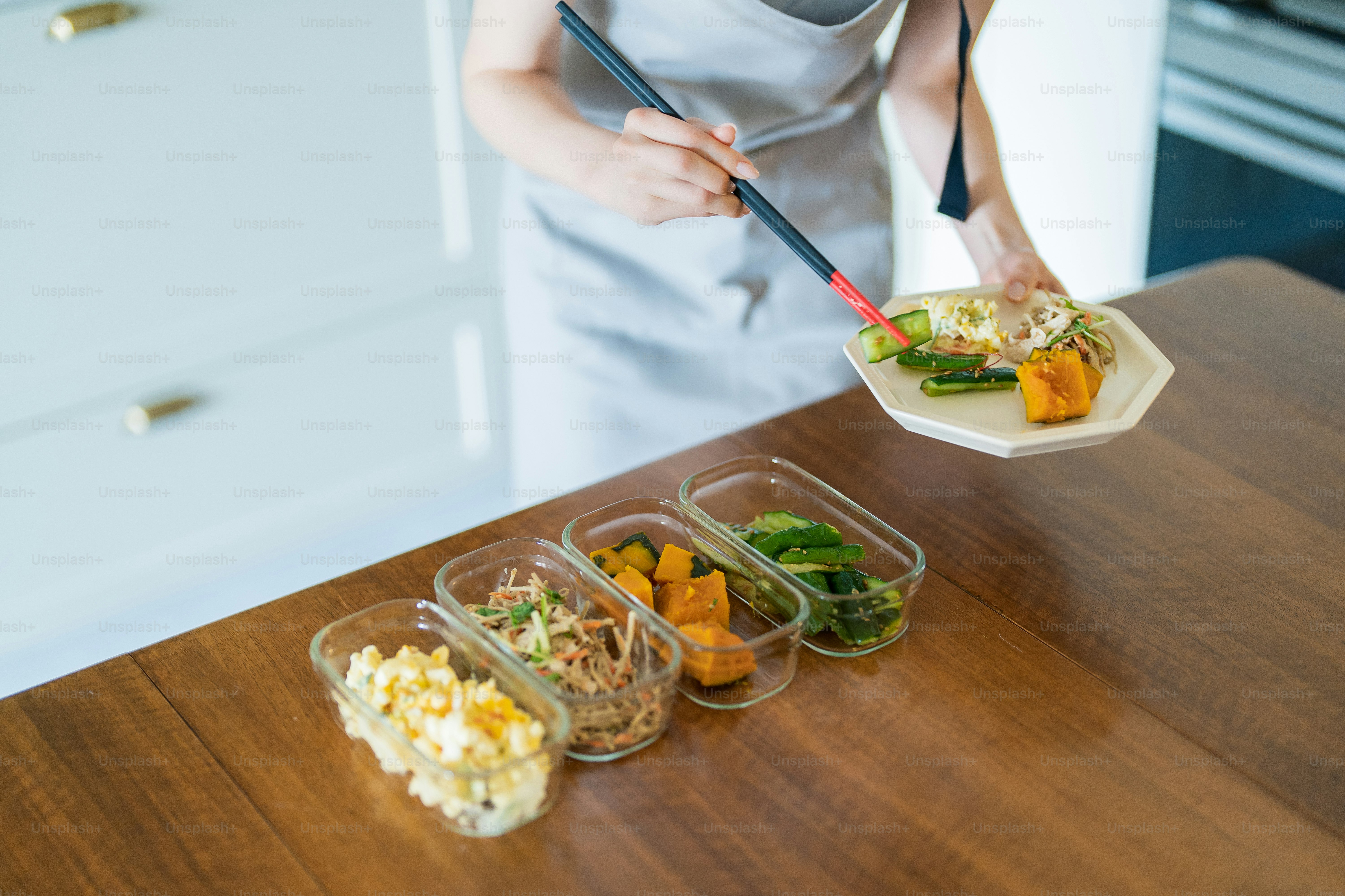 A woman who puts prepared side dishes on a plate on the table