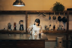 Une jeune femme prépare du café avec une goutte à goutte à la main dans un espace calmement éclairé