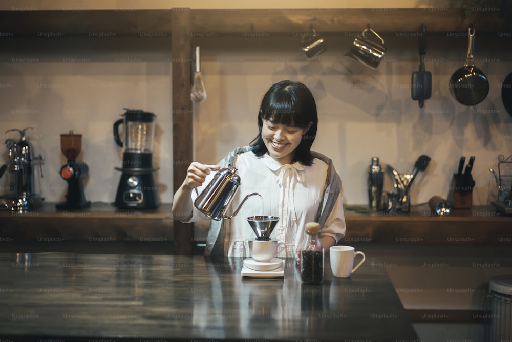 Uma jovem mulher preparando café com um gotejamento de mão em um espaço calmamente iluminado