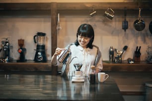 A young woman brewing coffee with a hand drip in a calmly lit space