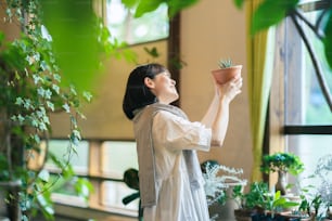 Una mujer joven mirando las plantas de follaje con una sonrisa