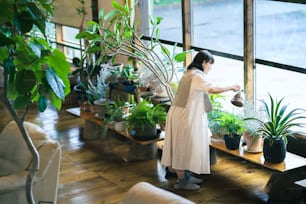 Une jeune femme regardant les plantes à feuillage avec un sourire