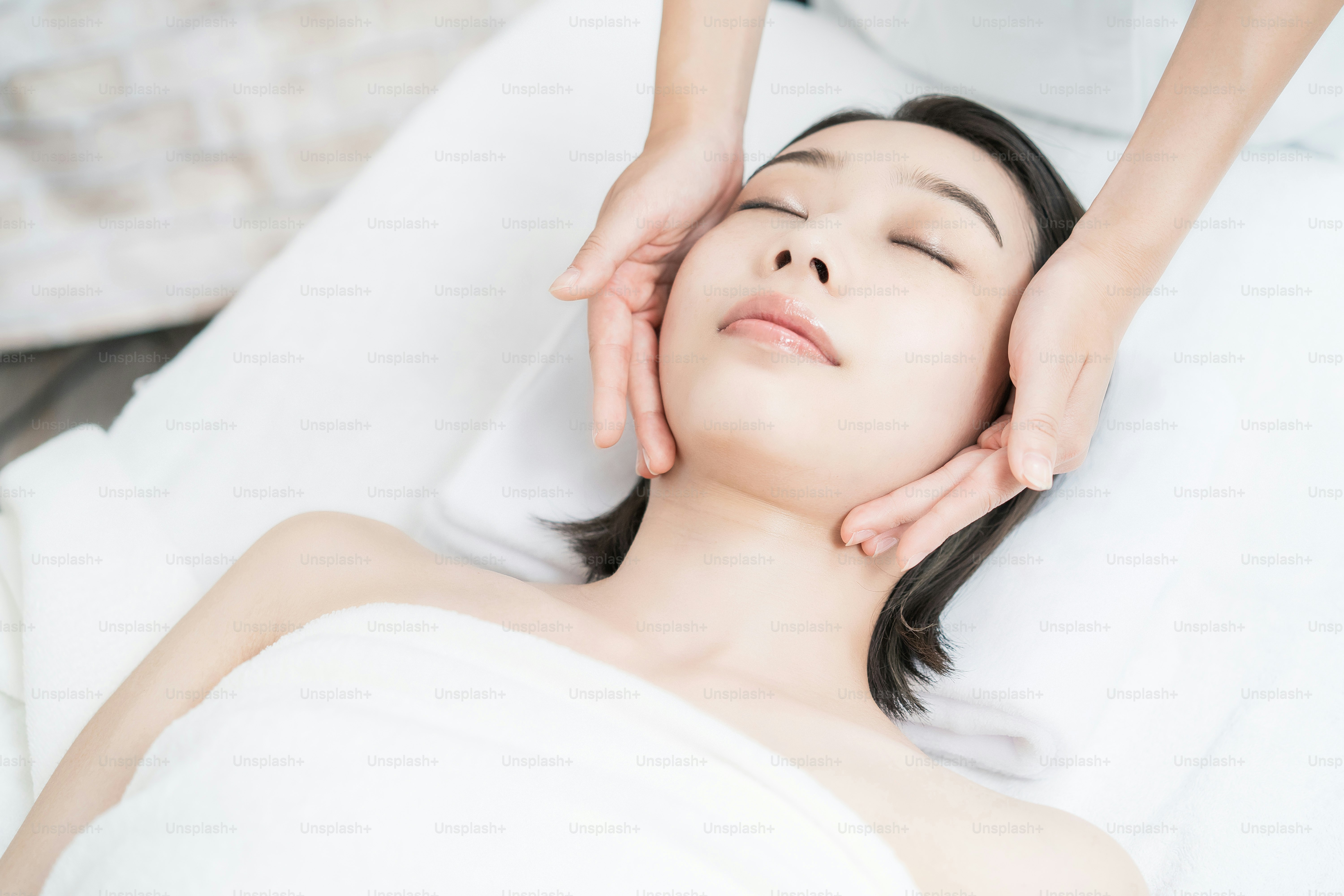 Asian young woman whose head is massaged at an esthetic salon
