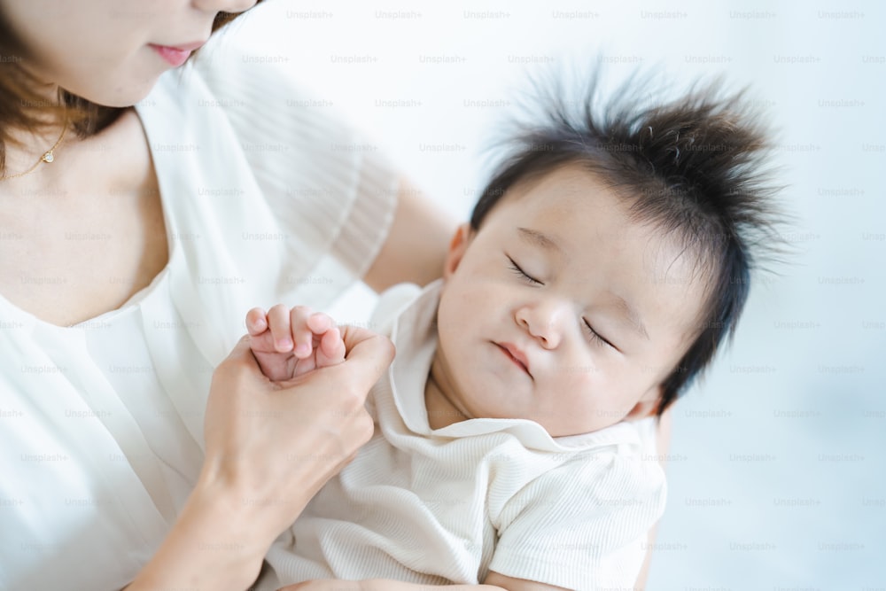Bebé asiático será abrazado en una habitación luminosa