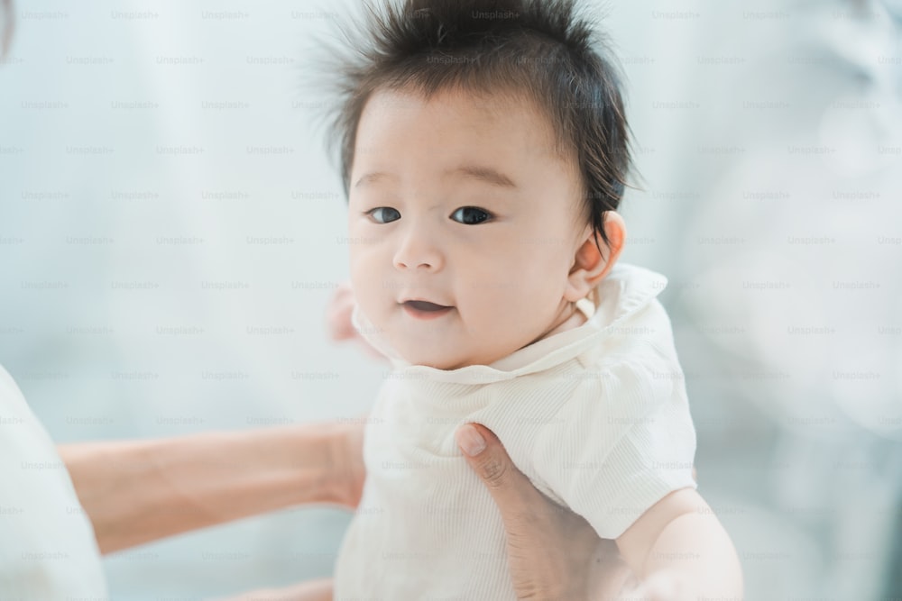 Asian baby to be hugged in a bright room