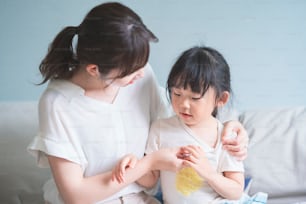 Una ragazza asiatica che fa misurare a sua madre la sua temperatura corporea