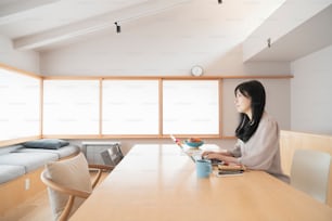 Asian black haired woman working from home using a laptop