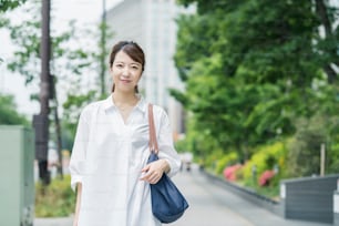 Asian young housewife in white shirt going out with shopping bag