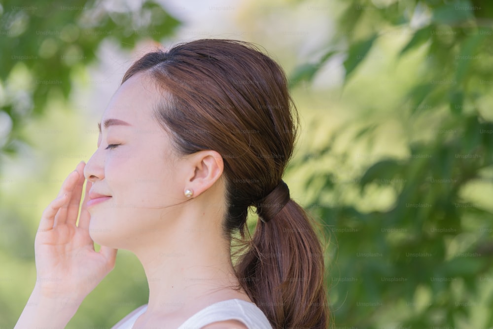 Asian (Japanese) young woman with beautiful skin surrounded by greenery