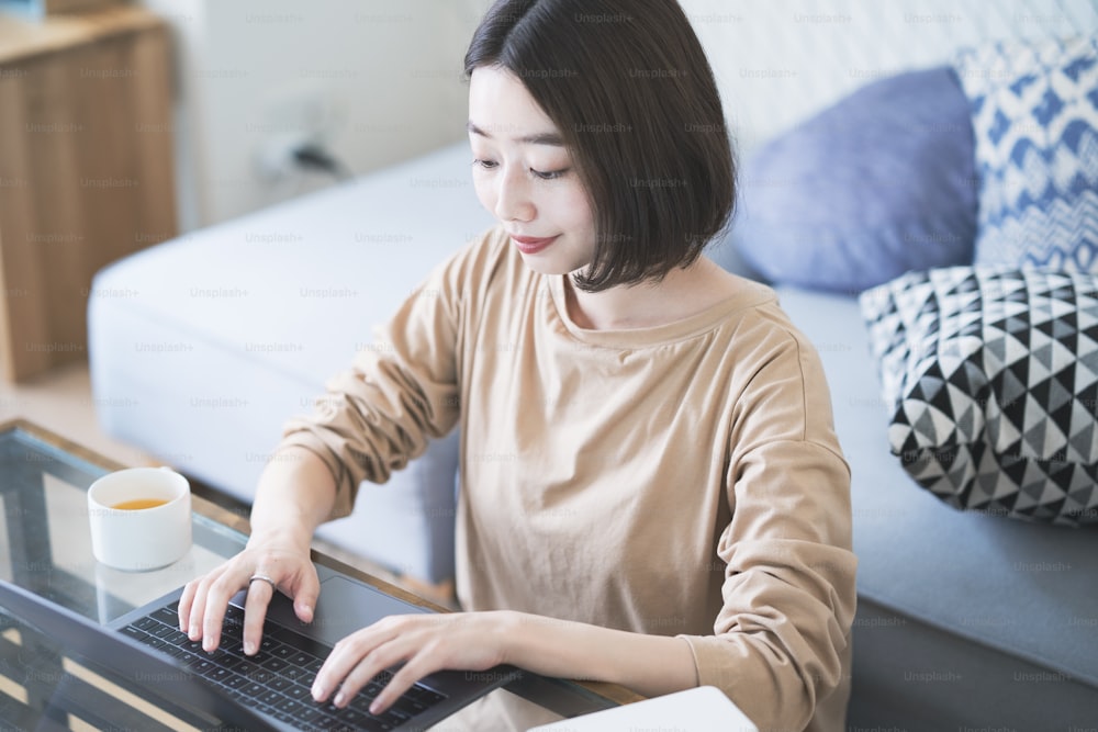 Giovane donna asiatica che lavora in remoto con il laptop in camera a casa