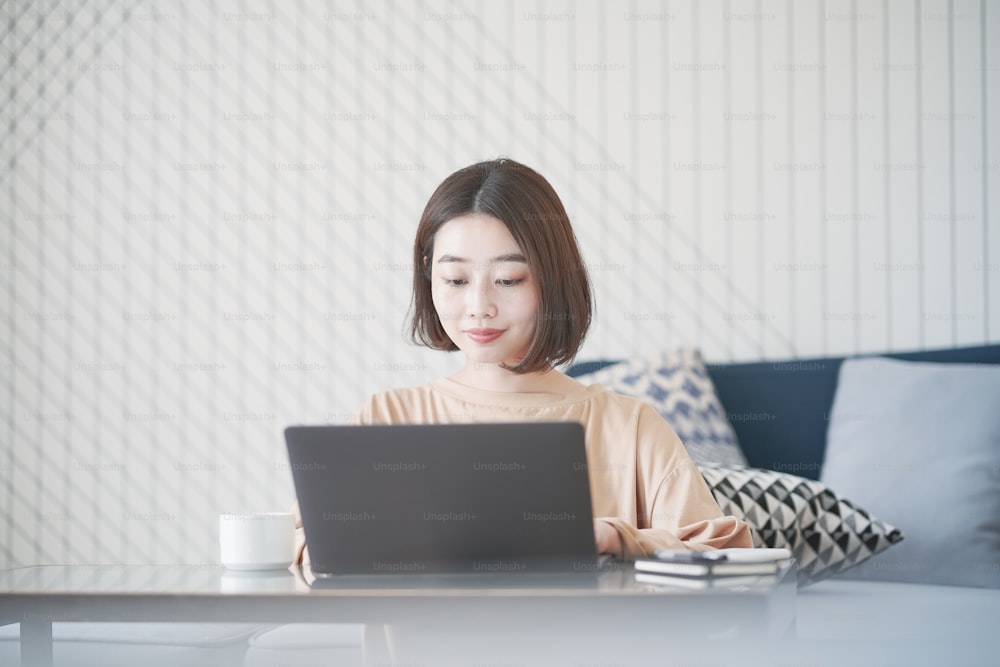 Giovane donna asiatica che lavora in remoto con il laptop in camera a casa
