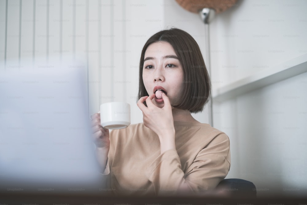 Mulher jovem asiática olhando para a tela do laptop na sala em casa