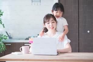 Mujer asiática haciendo teletrabajo en la sala de casa mientras juega con su hija