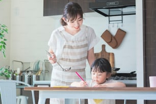 Una ragazza che disegna in cucina e una madre che veglia su di lei mentre cucina