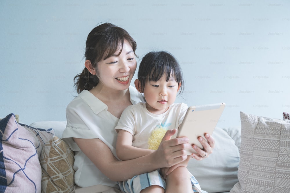 Mom and daughter sitting on a sofa and operating a tablet device