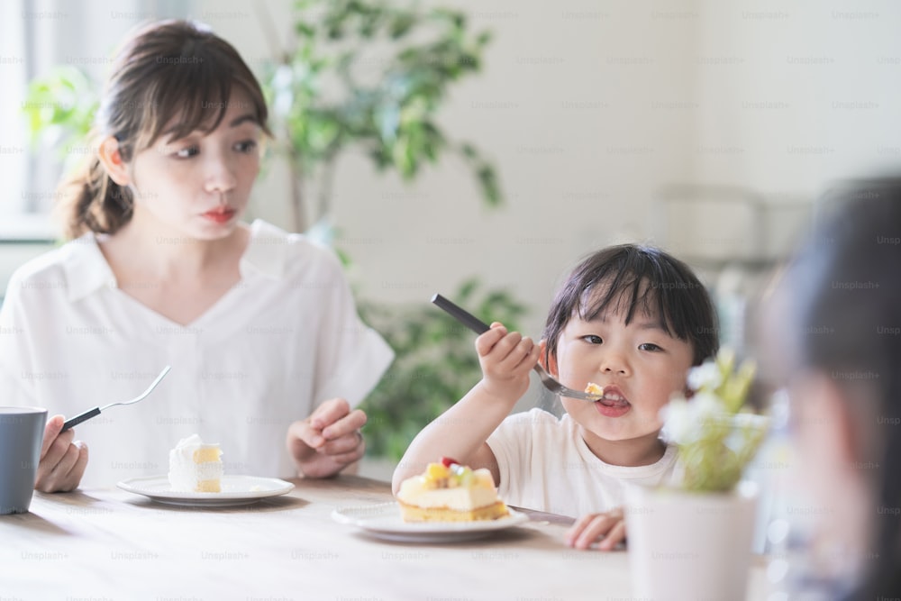 Mamma e figlia asiatiche che mangiano la torta al tavolo da pranzo a casa