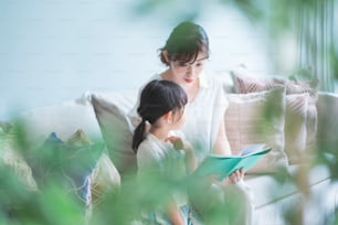 Mother and daughter sitting on the sofa and reading a picture book
