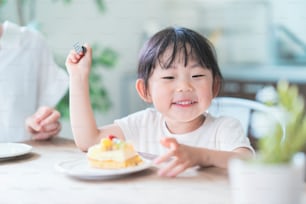 自宅の食卓でケーキを食べるアジアの母と娘