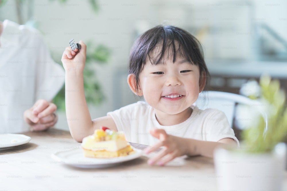 Asian mom and daughter eating cake at dining table at home