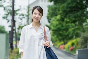 Giovane casalinga asiatica in camicia bianca che esce con la borsa della spesa