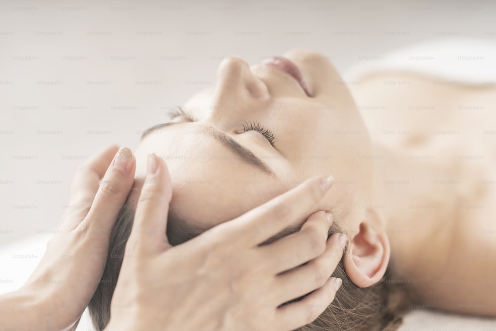 Mujer joven con un masaje en la cabeza en el salón de belleza